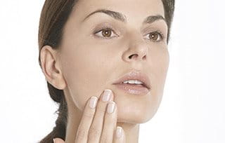 Woman moisturizing her face