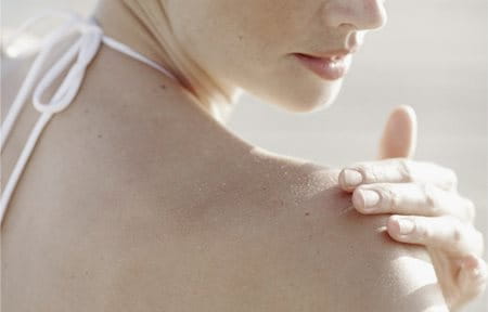 Woman applies sunscreen on her shoulder
