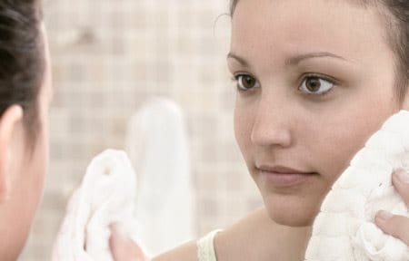 Young woman patting her face dry with towel