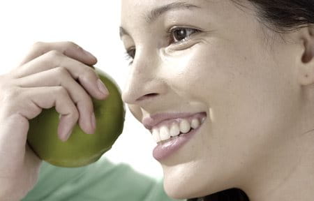 Woman smiling and holding a green apple in her hand