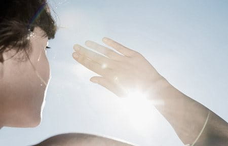 Femme se protégeant les yeux du soleil avec la main droite.
