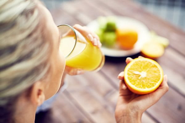 žena pije iscijeđeni sok od naranče