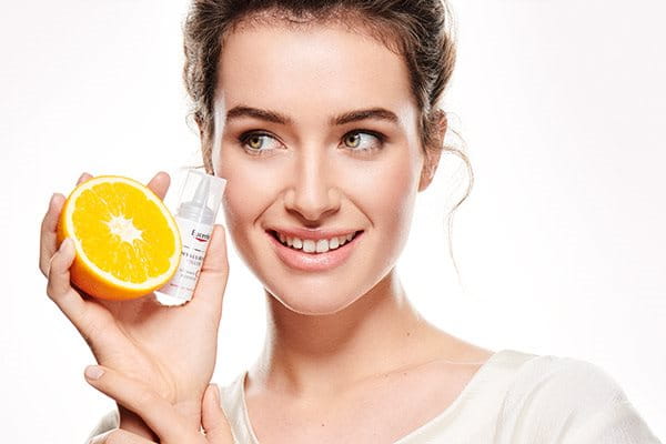 žena drži naranču i Eucerin Vitamin C Booster
