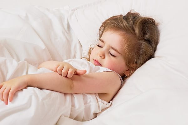 Little girl in bed scratching her arm