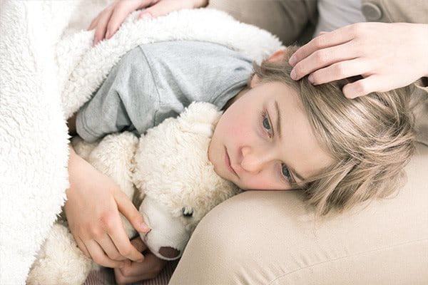 Little girl cuddling a teddy bear looking sad