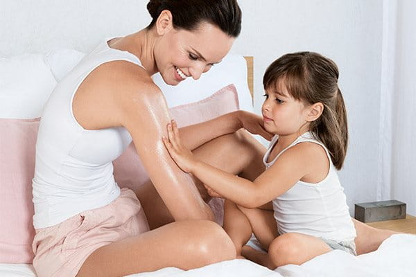 Little girl applying creme to her mother's arm