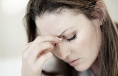 Woman looking down, stress pose – her hand is touching her forehead
