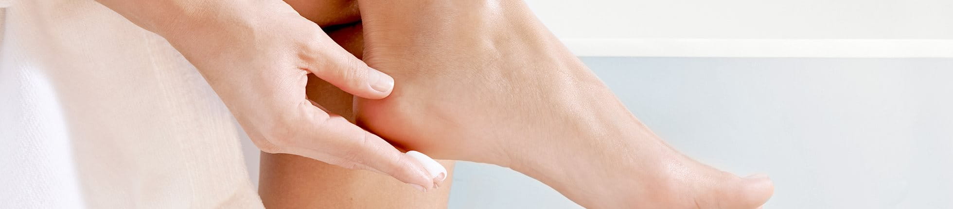 Woman applying lotion to the heel of her foot