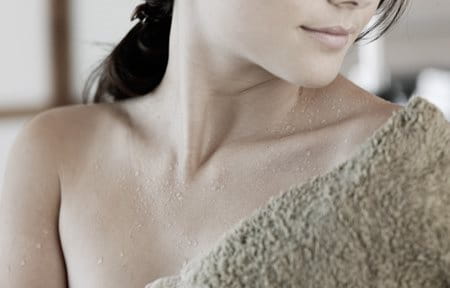 Eine Frau trocknet ihre Haut nach dem Duschen mit einem Handtuch ab. 