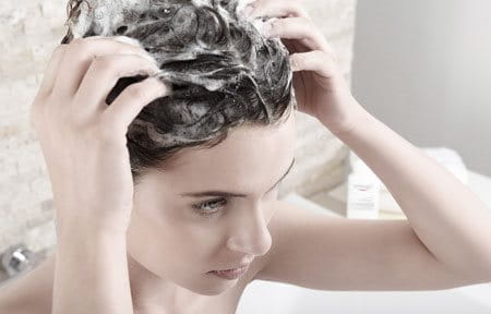 Eine Frau massiert Shampoo in ihre Haare ein