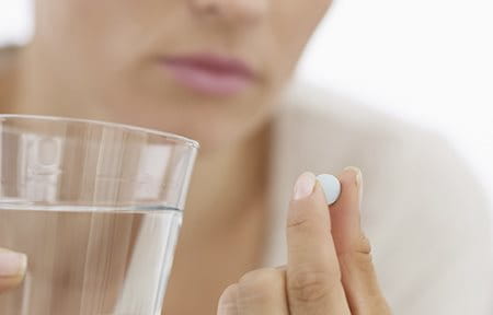 Woman about to take a pill with a glas of water