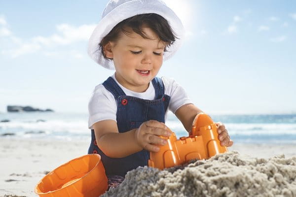 Barn i skyddande kläder som leker på en strand