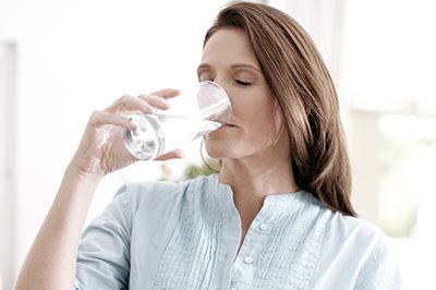 Frau trinkt aus Wasserglas