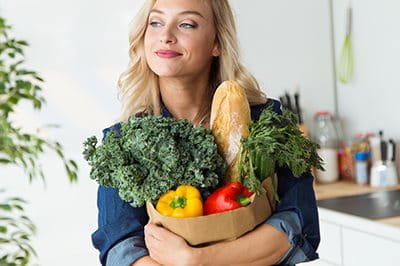 Frau trägt Einkaufstüte mit Gemüse
