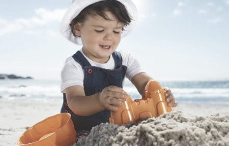 Spielendes Baby im Sand in der Sonne