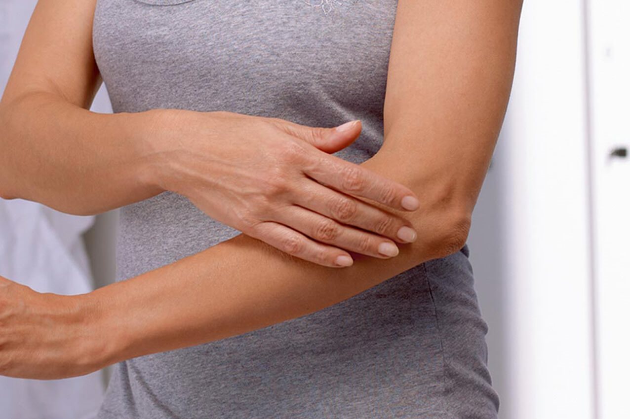 Frau greift ihren Ellenbogen an