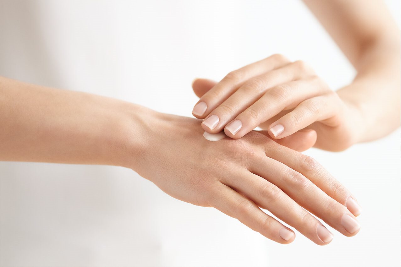 Frau cremet Hand ein