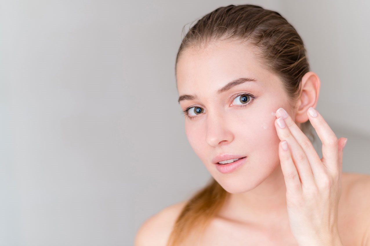 Frau cremt Gesicht ein