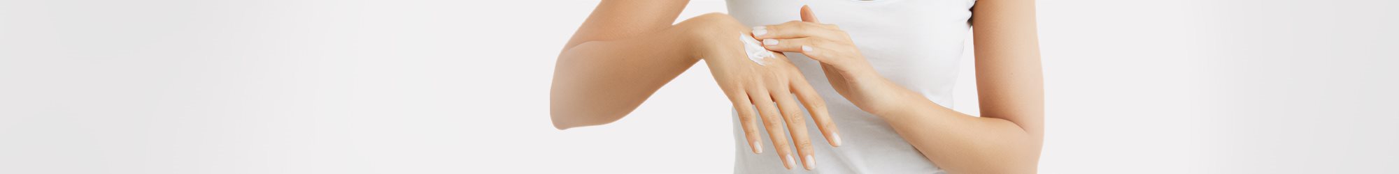 Vue rapprochée d'un mannequin féminin appliquant de la crème Eucerin Eczema Relief sur sa main droite, sur fond blanc.