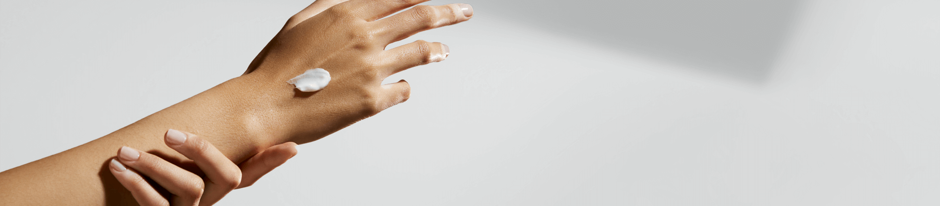 View of an arm and hand being stretched out with a cream product placed on top of the hand.