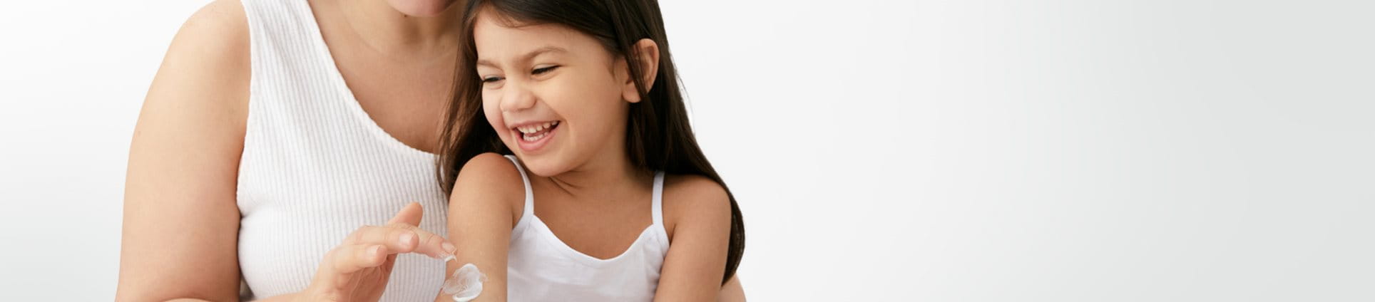 Gros plan d'une femme mannequin portant un short de couleur pâle et montrant du produit en crème étendu sur sa cuisse gauche.