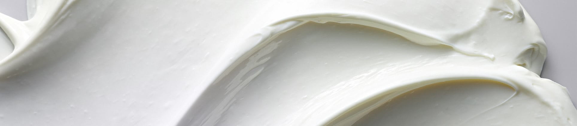 Vue d’une crème épaisse Eucerin étalée sur un fond gris.