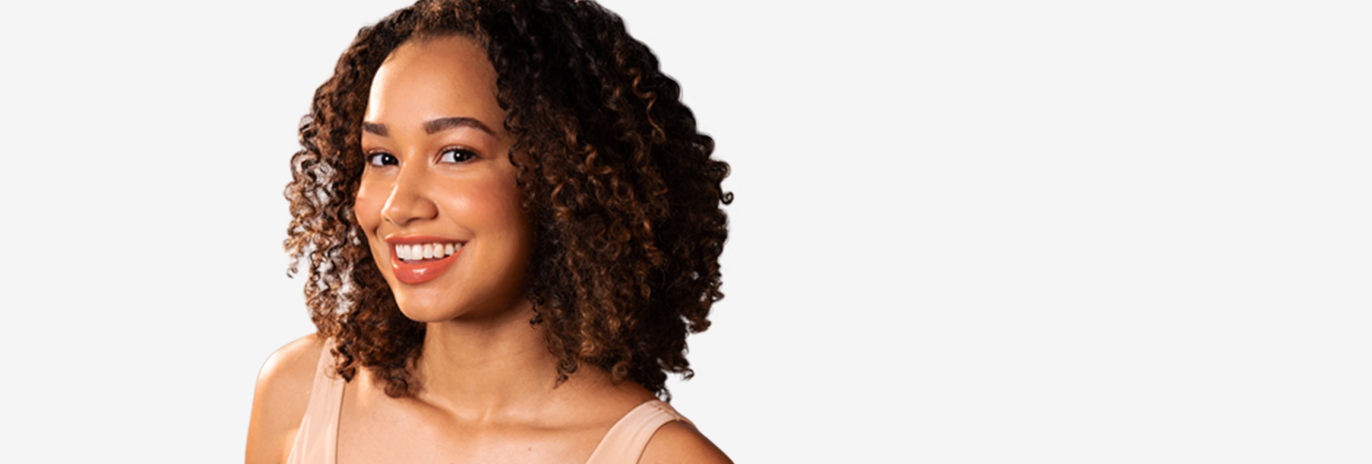 View of a person with brown curly hair smiling against a white background.