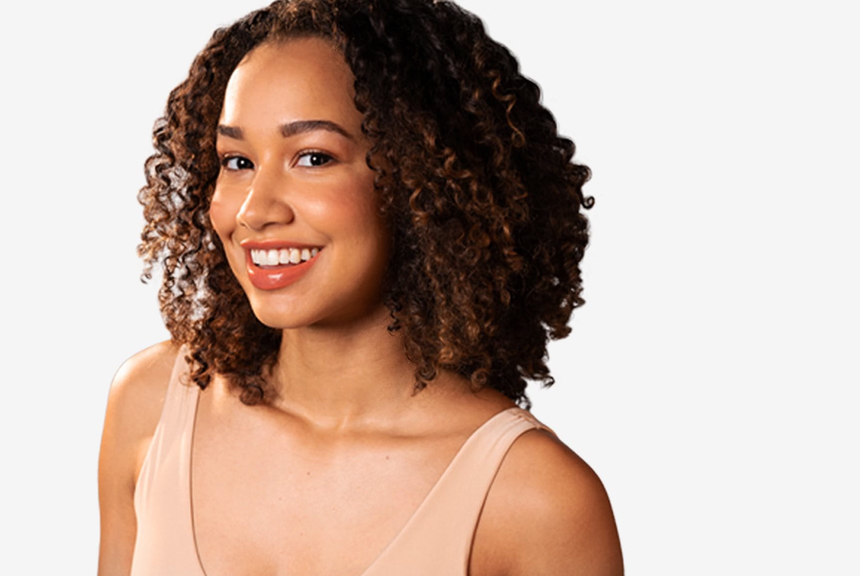 View of a person with brown curly hair smiling against a white background.