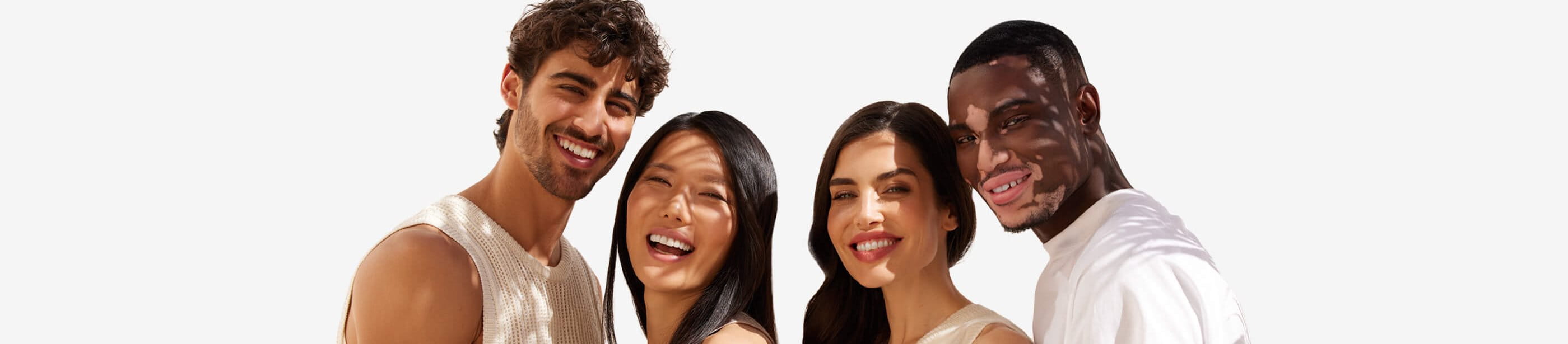 View of four people smiling while embracing each other and looking straight at the camera.