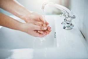 Mains lavées sous un robinet d‘eau. 