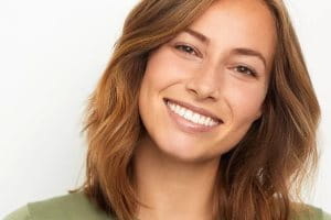 Sourire d'une femme avec des premières rides du visage, exprimant une beauté naturelle et une attitude positive.