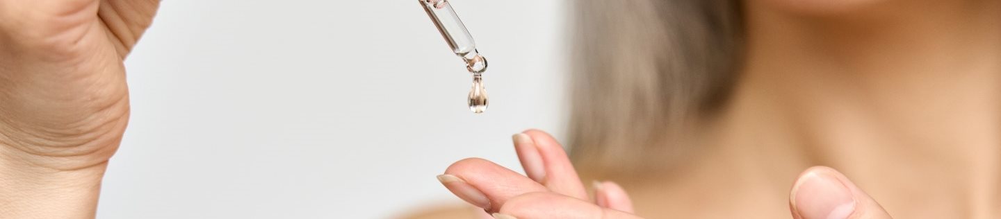 Gros plan sur une femme qui verse du sérum sur sa main.