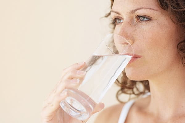  Brünette Frau trinkt Wasser aus einem Glas 