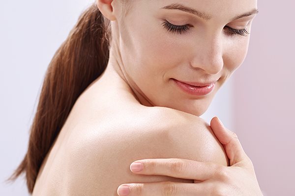 Frau betrachtet Haut auf ihrer Schulter