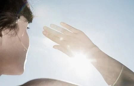 Frau schirmt Gesicht von der Sonne ab