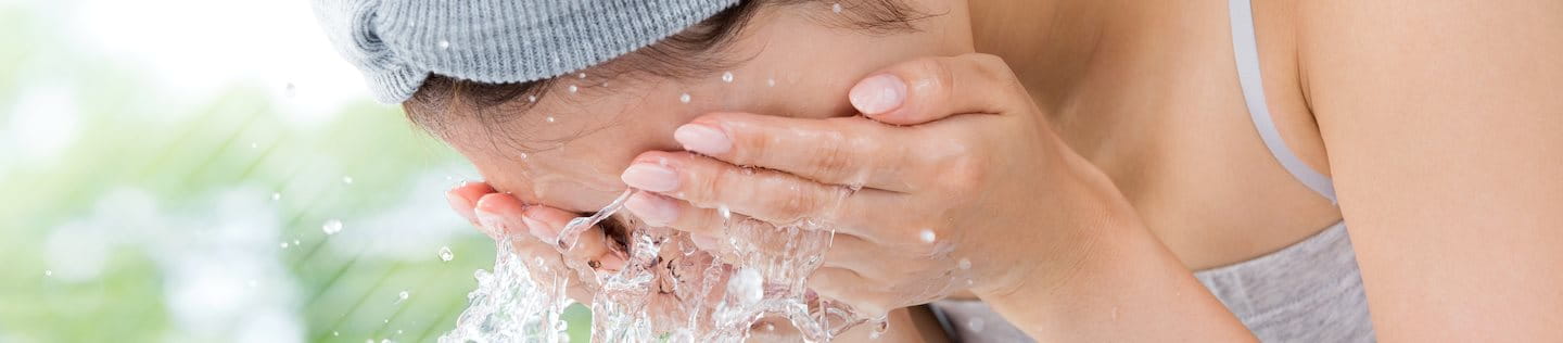 Frau wäscht Gesicht mit Wasser