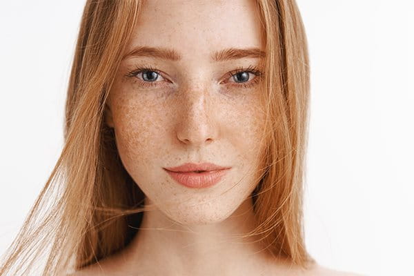 Femme aux cheveux roux avec des taches de rousseur sur le visage.