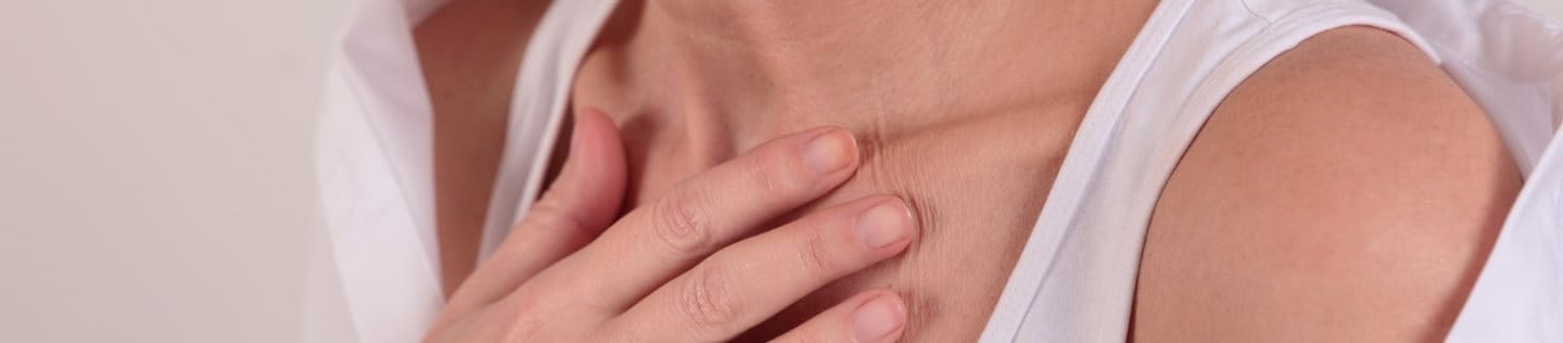 Frau legt eine Hand auf das Dekolleté