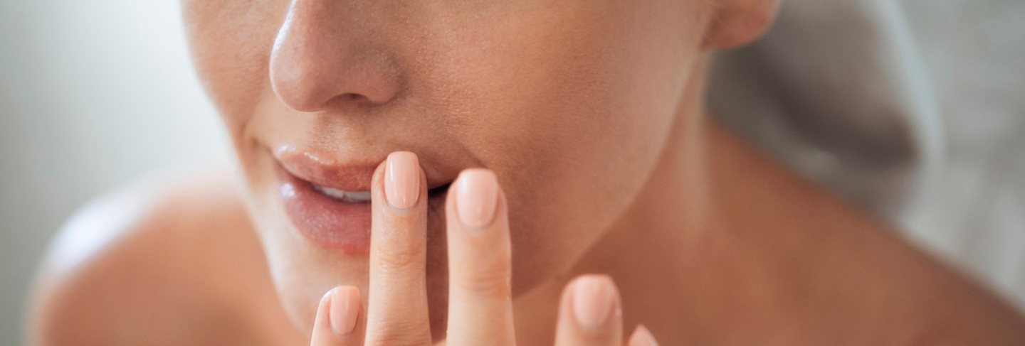 Frau trägt Lippenpflege mit den Fingern auf