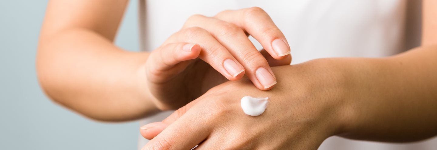 Nahaufnahme der Hand einer Frau, die Feuchtigkeitscreme aufträgt