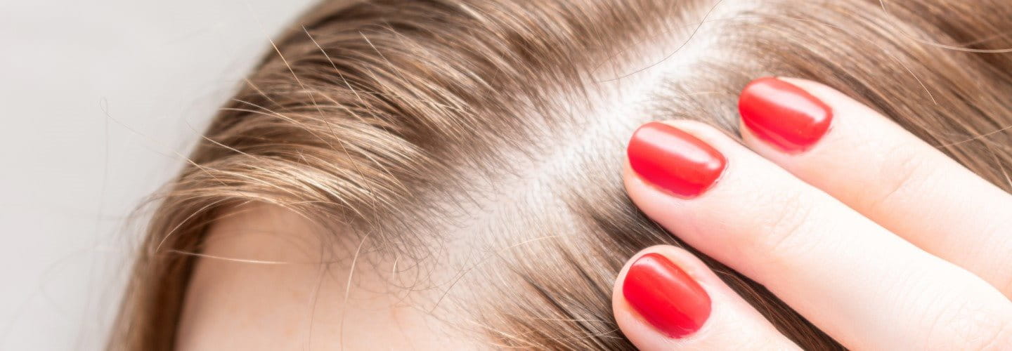 Frau berührt ihren Scheitel.