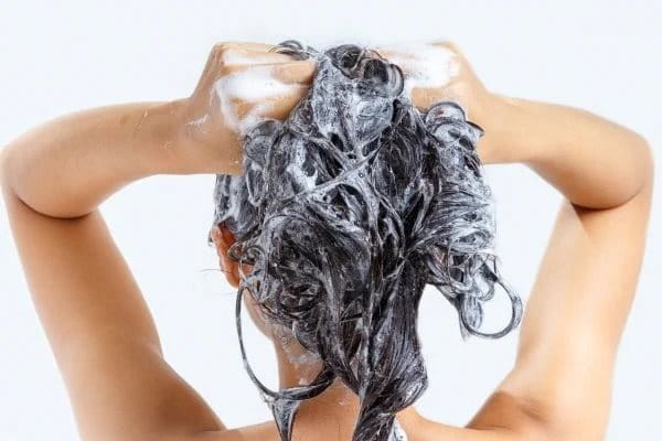 Eine Frau von hinten mit Shampoo in den Haaren