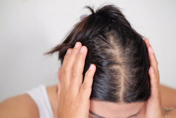 Frau fasst sich mit beiden Händen an den Kopf