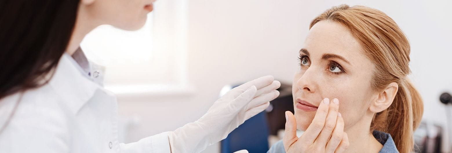 A woman having her face inspected by a doctor 