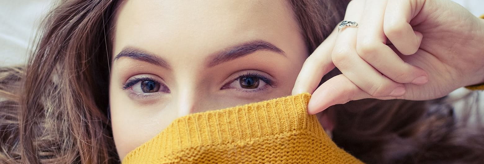 Woman covering the bottom half of her face with a sweater