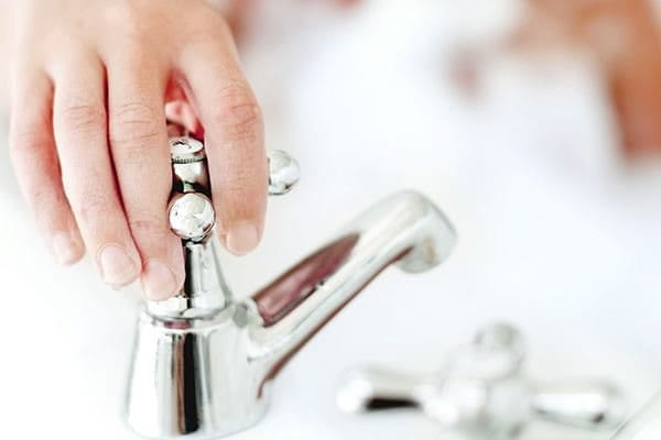 Close-up of a young woman's hand turning a tap on