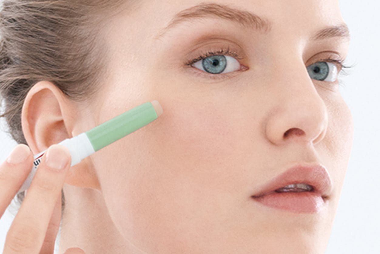 woman applying acne cover stick