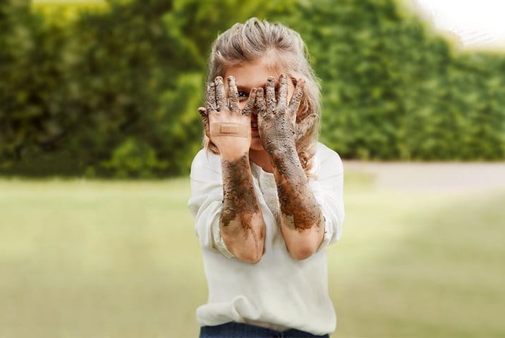 A young girl with dirt-covered hands but a clean plaster
