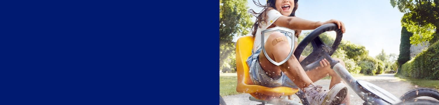 A girl has fun riding a go kart, on her knee a Hansaplast Elastic Plaster.