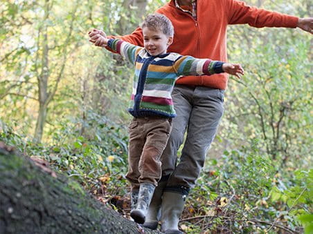 Vater und Kind balancieren auf einem Baumstamm